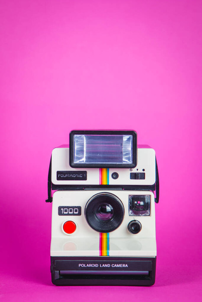 Cámara fotográfica Polaroid sobre fondo rosa vibrante
 - Foto, Imagen