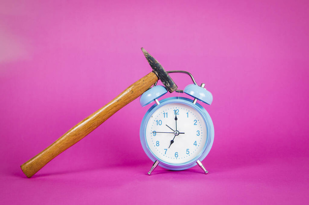 Hermoso reloj despertador azul pastel retro sobre un vibrante fondo rosa con la mano y un martillo
 - Foto, Imagen