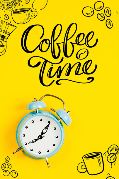 Синий будильник с графикой и текстом Время кофе на желтом фоне
 - Фото, изображение