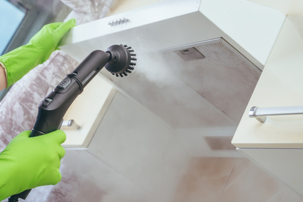 limpeza da casa. Menina escova limpadores de vapor desenho de cozinha com vapor em luvas verdes. limpeza de uma superfície. cozinha leve
 - Foto, Imagem