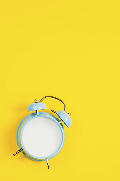 Reloj despertador en blanco azul vintage sobre fondo amarillo
 - Foto, imagen