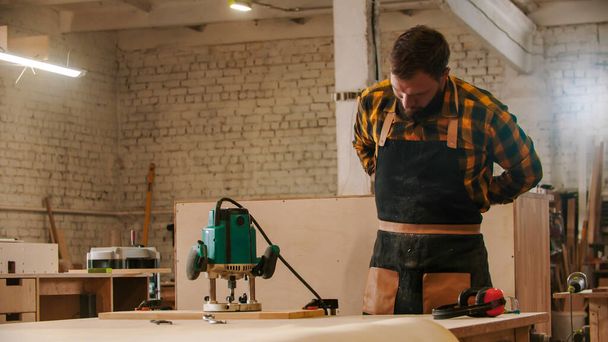 Tischlerei - Arbeiter zieht sich Schürze an - Foto, Bild