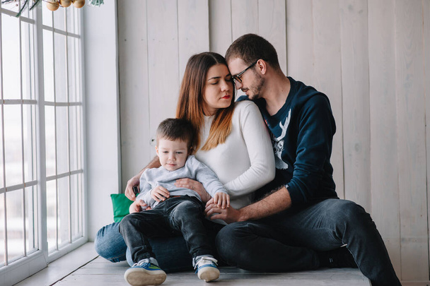 happy family of mother, father and child son playing and cuddling, at home on floor near a big window. Family concept - Photo, Image