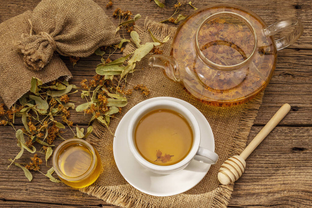 Linden tea. Dry fragrant flowers. Sunny morning breakfast. Hot drink to strengthen the immune system, alternative medicine. Vintage wooden table - Photo, Image