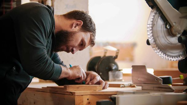 Trabalho de carpintaria - homem barbudo fazendo marcas na madeira compensada
 - Foto, Imagem