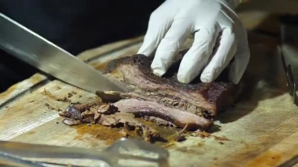 Közelíts rá a kezedre egy füstölt marhaszegyet tartva egy vágódeszkán, és gyorsan szeleteld vékony szeletekre a főtt marhahúst egy grillezéshez.. - Felvétel, videó