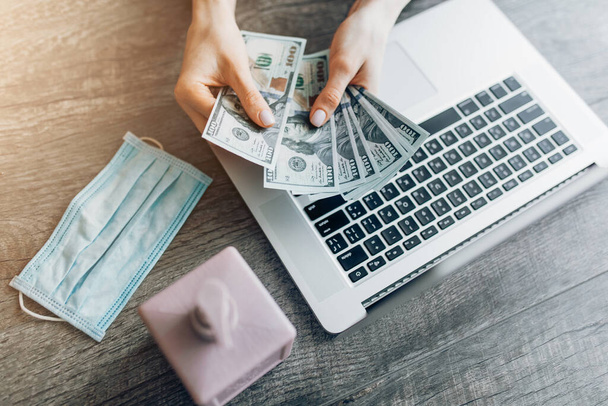 Close-up de mãos contando dinheiro, salário no fundo de um laptop. Conceito de trabalho remoto, quarentena e coronavírus
, - Foto, Imagem