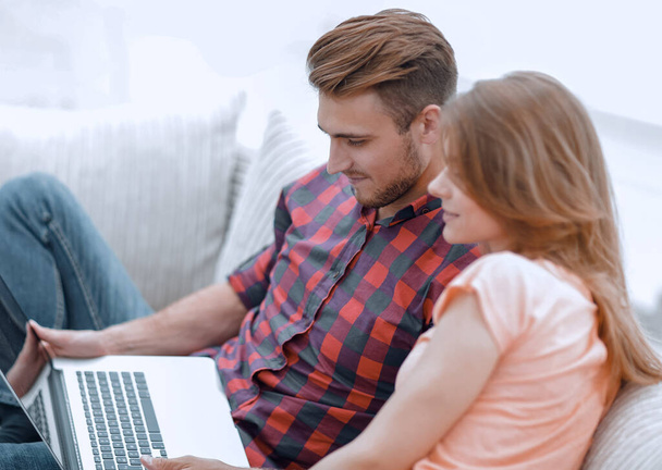 young man and girl with laptop sitting on sofa - Photo, Image