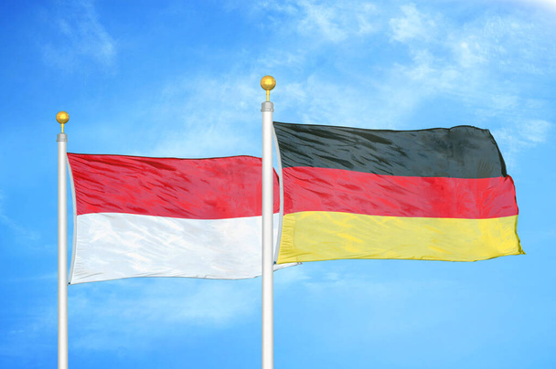 Indonezja i Niemcy dwie flagi na maszcie flagowym i niebieskie zachmurzone tło nieba - Zdjęcie, obraz
