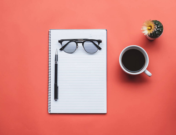 Bovenaanzicht afbeelding van notebook met kopje koffie en glazen op oranje achtergrond. - Foto, afbeelding