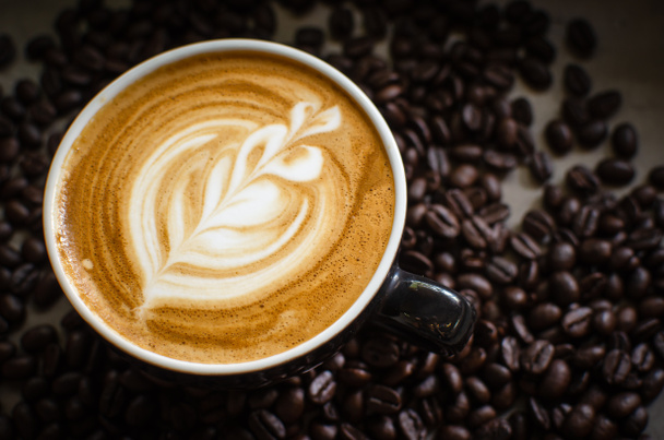 arte latte caliente en taza roja contra granos de café
 - Foto, Imagen