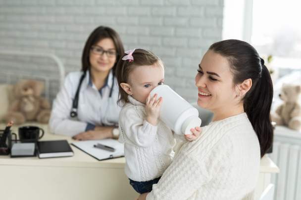 Portrait of mother and child at a doctors appointment. Pediatrician meeting with mother and child in hospital - Фото, изображение