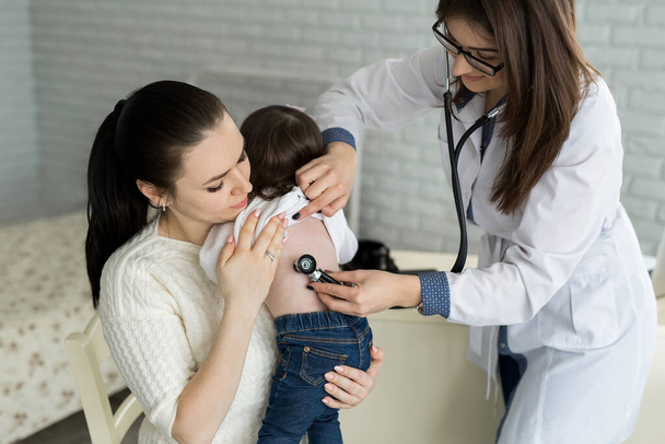 Professional general medical pediatrician doctor in white uniform gown listen lung and heart sound of child patient with stethoscope: Physician check up kid female after consult in hospital. - Фото, зображення