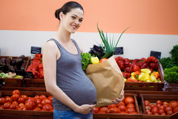 Fiatal terhes nő vásárol egy zöldségboltban - Fotó, kép