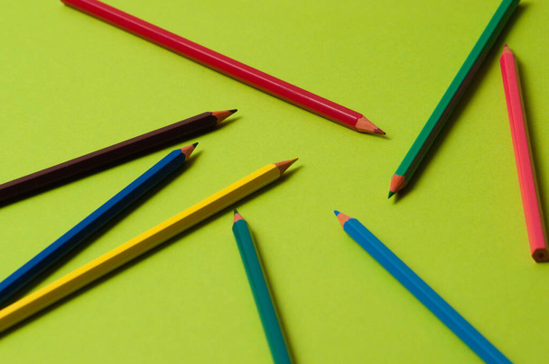 Pencils of different colors on green design paper. - Photo, Image