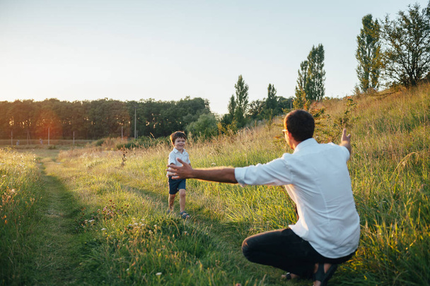 Handsome dad with his little cute son are having fun and playing on green grassy lawn. Happy family concept. Beauty nature scene with family outdoor lifestyle. family resting together. Fathers day - Foto, immagini