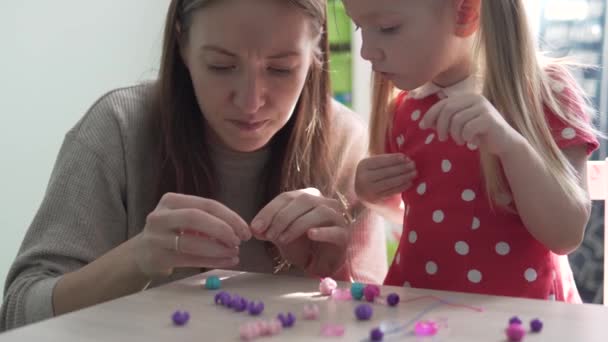 Mom and daughter make a bracelet on hand - Footage, Video