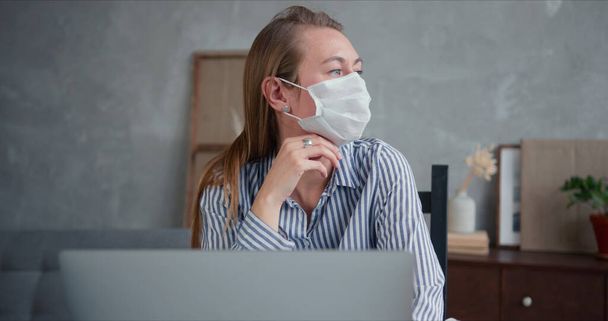 Young professional doctor woman using laptop to help and consult people from home online on quarantine wearing face mask - Foto, Bild