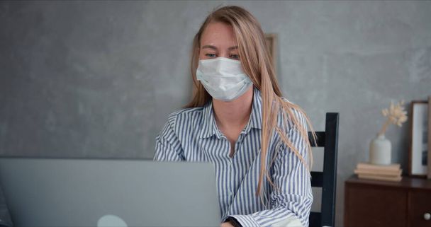Junge professionelle Ärztin mit Laptop hilft und berät Menschen von zu Hause aus online über Quarantäne mit Gesichtsmaske - Foto, Bild