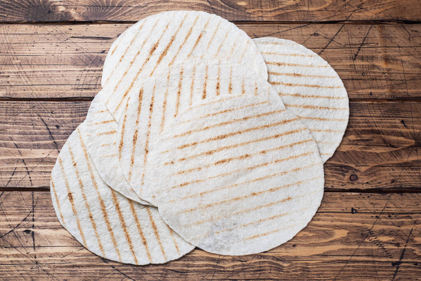 Empty tortillas made on the grill. Wooden background Copy space - Foto, Bild