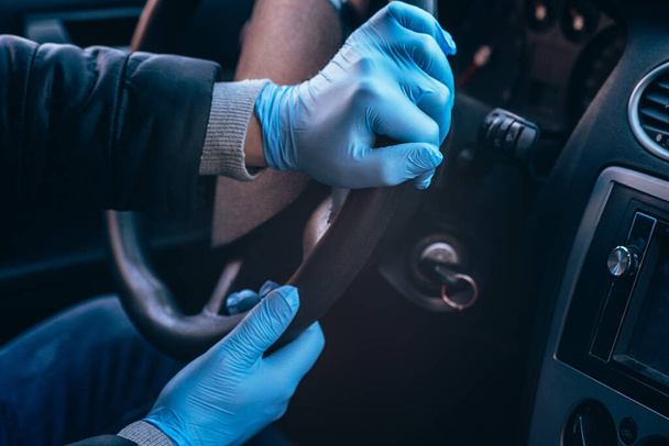 A man holds the steering wheel of a car in protective medical gloves. Hands close-up. Safe drive in a taxi during pandemic coronavirus. Protect driver and passengers from bacteria and virus infection. - Foto, Imagen