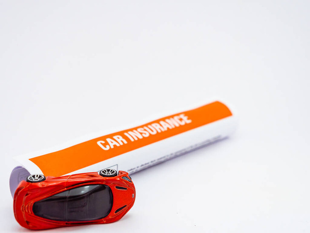 A rolled car toy and roll of insurance papers shot on white back - Photo, Image