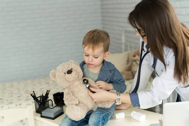 Doktor ve çocuk hastanedeki oyuncak ayıyı muayene ediyor.. - Fotoğraf, Görsel