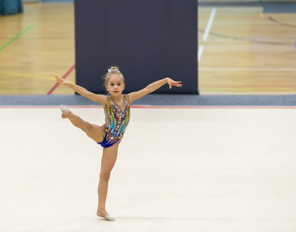 Porträt einer jungen Turnerin. Porträt eines 7-jährigen Mädchens bei rhythmischen Turnwettkämpfen - Foto, Bild