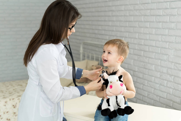 Médico pediatra médico general profesional vestido de uniforme blanco escuchar el sonido del pulmón y el corazón del paciente infantil con estetoscopio
 - Foto, imagen