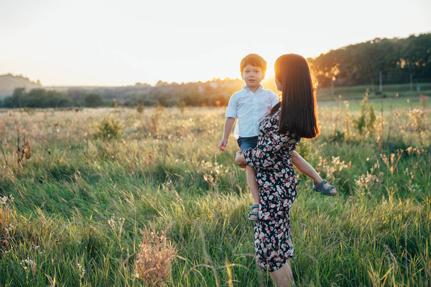 Stilish mother and handsome son having fun on the nature. Happy family concept. Beauty nature scene with family outdoor lifestyle. Happy family resting together. Happiness in family life. Mothers day. - Foto, Imagen