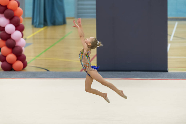 Портрет молодої гімнастки. Портрет 7-річної дівчинки на змаганнях з художньої гімнастики
 - Фото, зображення