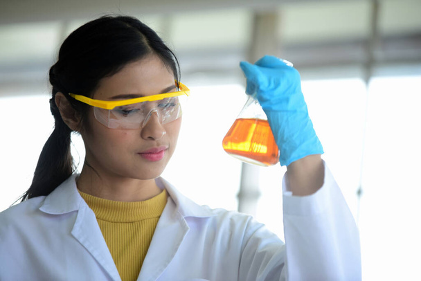 mujer científica asiática en laboratorio con probeta
 - Foto, Imagen