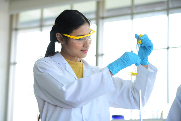 portret van Aziatische vrouwelijke onderzoeker in beschermende uniform houden reageerbuis in laboratorium - Foto, afbeelding