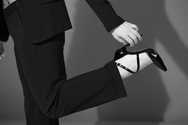 Κομψό γυναίκα κρατώντας το τακούνι του μαύρου λακαρισμένα παπούτσια υψηλής φτέρνας, μαύρο και άσπρο, έννοια της μόδας, κοντά - Φωτογραφία, εικόνα