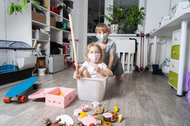 Maskeli çocuklar oyuncaklarla oynar ve beyaz bir kutuya binerler. Aile portresi. - Fotoğraf, Görsel