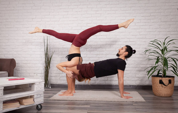 Giovane coppia divertirsi a casa con alcune pose acro yoga in luoghi diversi
. - Foto, immagini