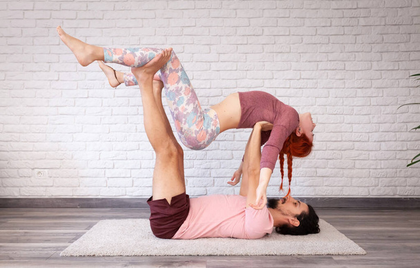Young couple having fun at home with some acro yoga poses in different places. - Photo, Image