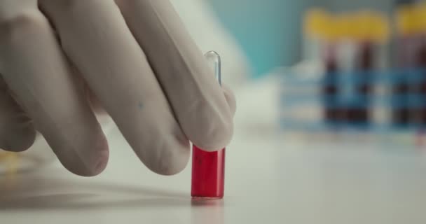 Close-up laboratóriumi tudós laboratóriumi asszisztens kesztyű kémcsövek pipetta vírus ampulla vörös reagensek vakcina fehér háttér - Felvétel, videó