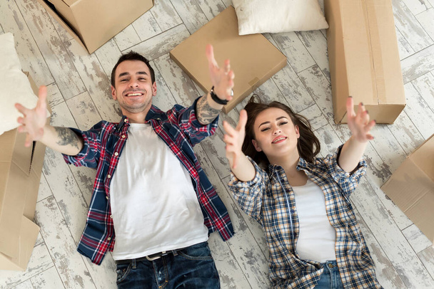 Haus, Leute, Reparatur und Immobilienkonzept - glückliches Paar mit Pappkartons und Sachen, die auf dem Boden liegen, an neuen Platz. - Foto, Bild