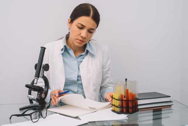 A beautiful female medical or scientific researcher using her microscope in a laboratory. - Foto, Bild