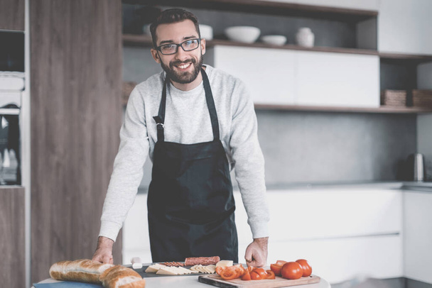 man in an apron slicing salami for sandwiches - Fotó, kép