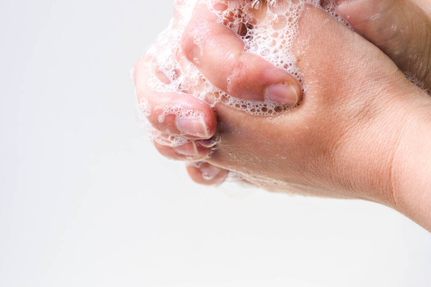 Гигиена и защита рук от вирусов (коронавирусов) и бактерий с использованием мыла. Процесс надлежащего мытья рук и пальцев с мылом вспененный водой крупным планом на белом фоне
 - Фото, изображение