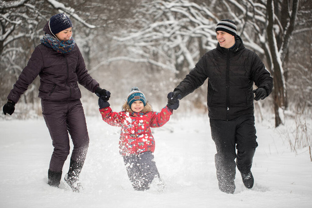 Ευτυχισμένη οικογένεια τρέχει στο χιόνι το χειμώνα. - Φωτογραφία, εικόνα