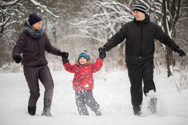 Ευτυχισμένη οικογένεια τρέχει στο χιόνι το χειμώνα. - Φωτογραφία, εικόνα
