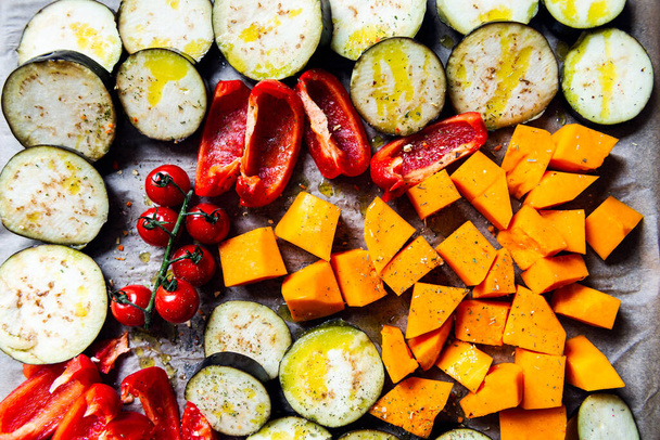 Desintoxicação saudável Jantar de diferentes vegetais, como beringela, pimenta vermelha, tomate cereja, abóbora. Fatias de legumes crus preparados para a assadura, refeição familiar simples
 - Foto, Imagem