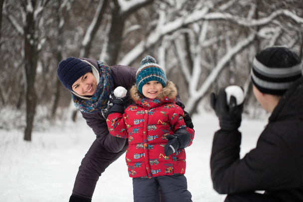 Father, mother and son playing at snowballs in winter Park. - Photo, Image