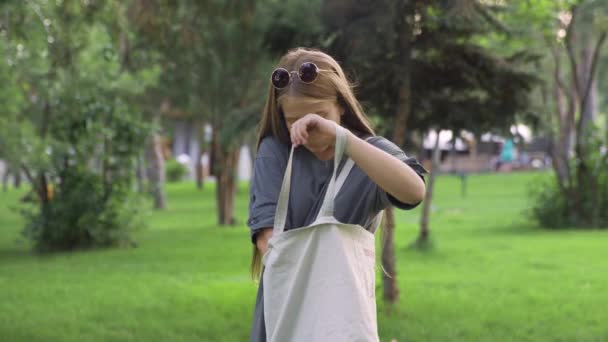 Young girl in sunglasses drinking orange juice outdoors at summer park - Filmagem, Vídeo