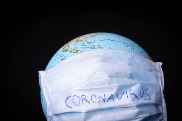 medical mask on a globe for coronavirus protection - Foto, afbeelding