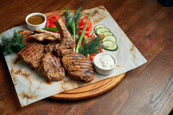 Juicy and mouth-watering grilled ribeye steak with spicy butter on a black tray with a side dish of vegetables. American cuisine.. Close up. Wooden background - Foto, Imagem