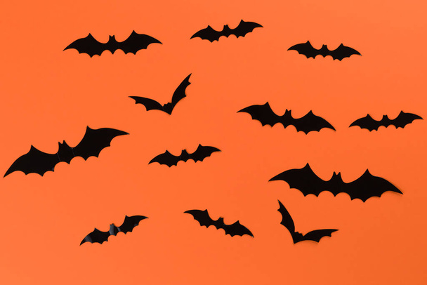 Halloween concept with many black horrible bats flying in a circle. Scary halloween flat lay composition on an orange background - Photo, Image